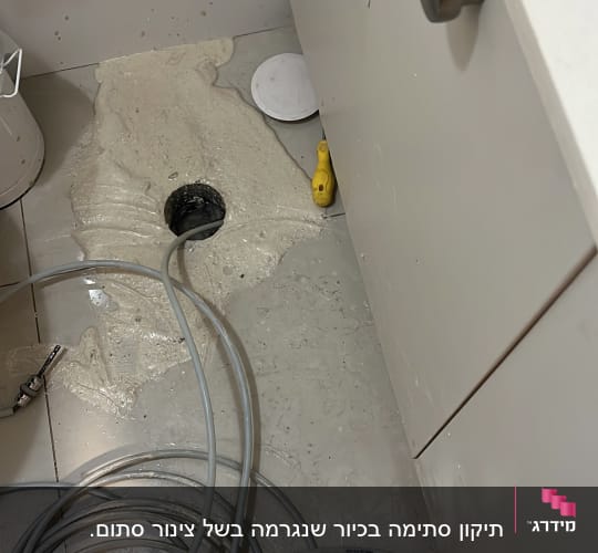 פתיחת סתימה בפתח ניקוז ברצפת חדר רחצה באמצעות קפיץ אינסטלציה